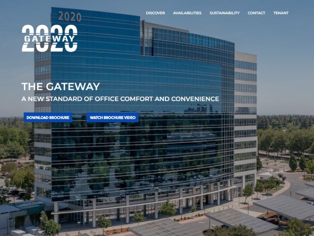 Modern glass office building with trees and a blue sky, labeled 2020 Gateway.